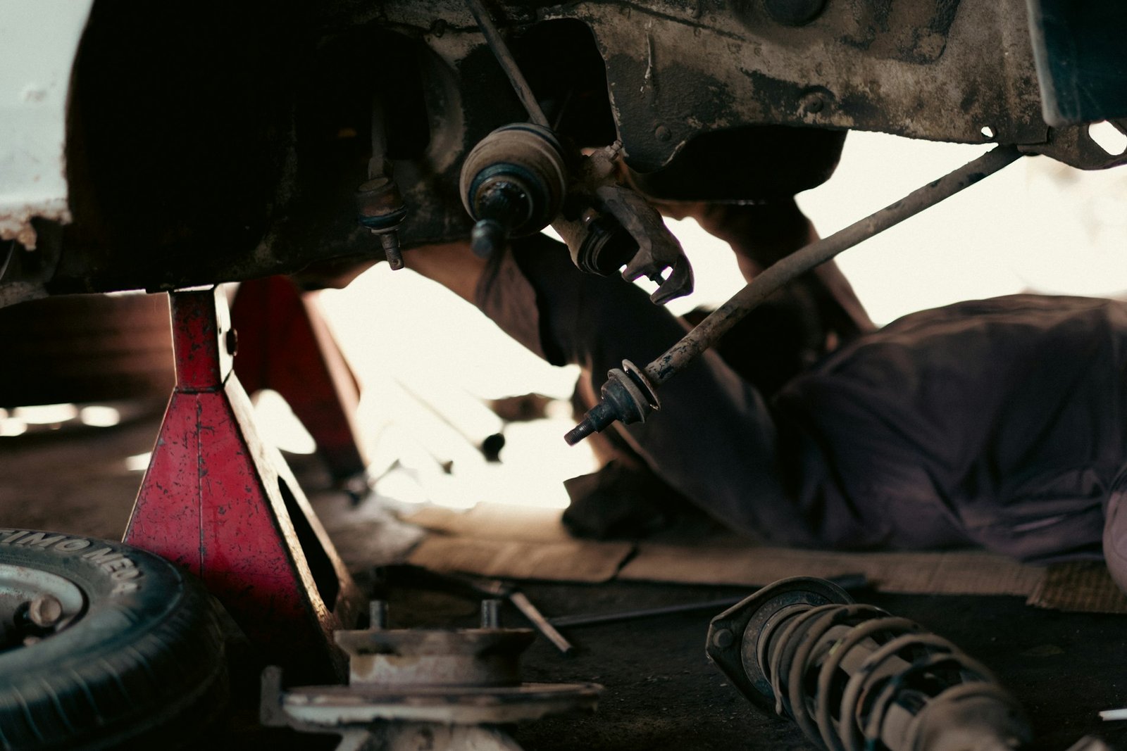 Mecánico trabajando bajo un coche elevado en un taller