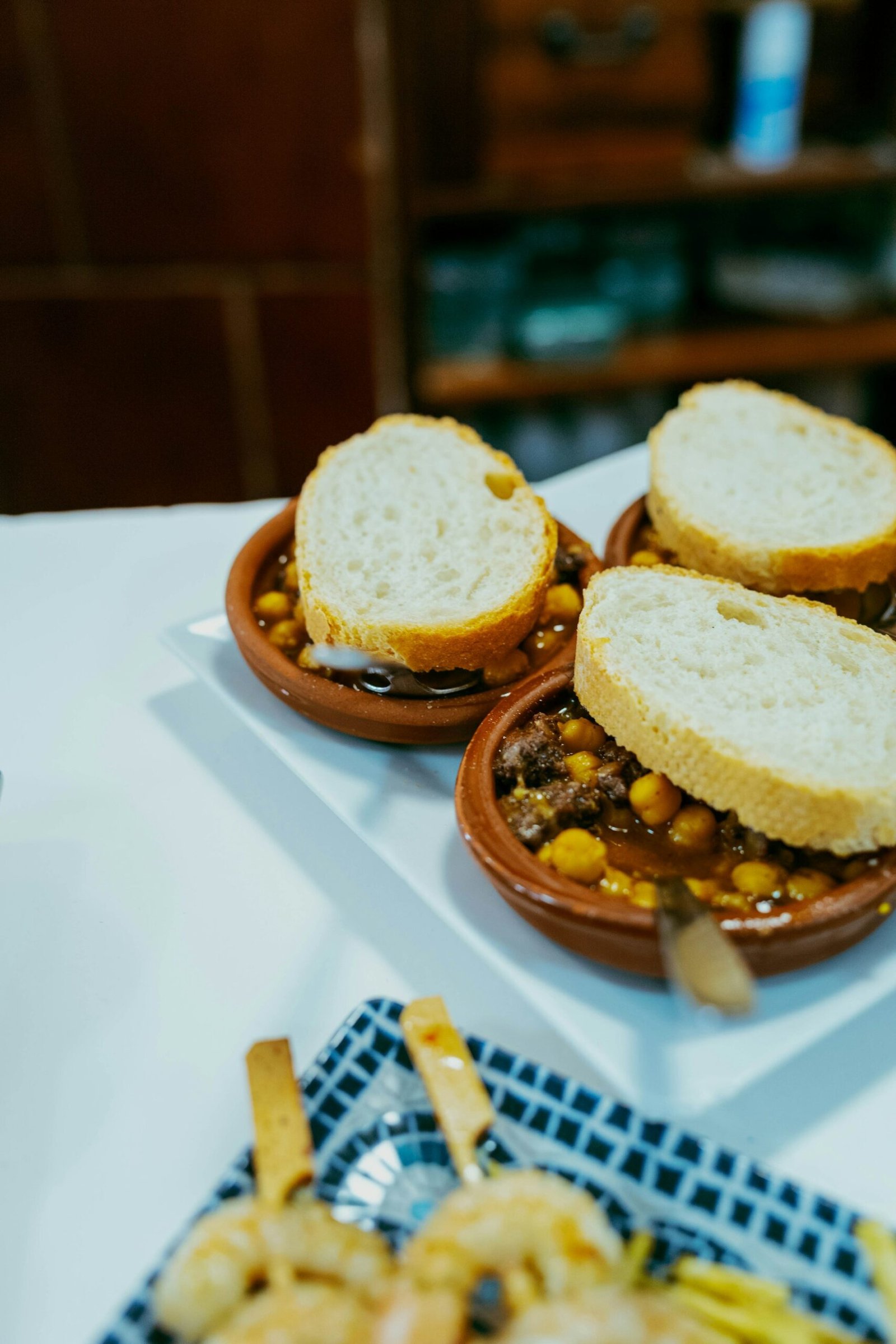 Cuencos de barro con garbanzos y carne acompañados de pan